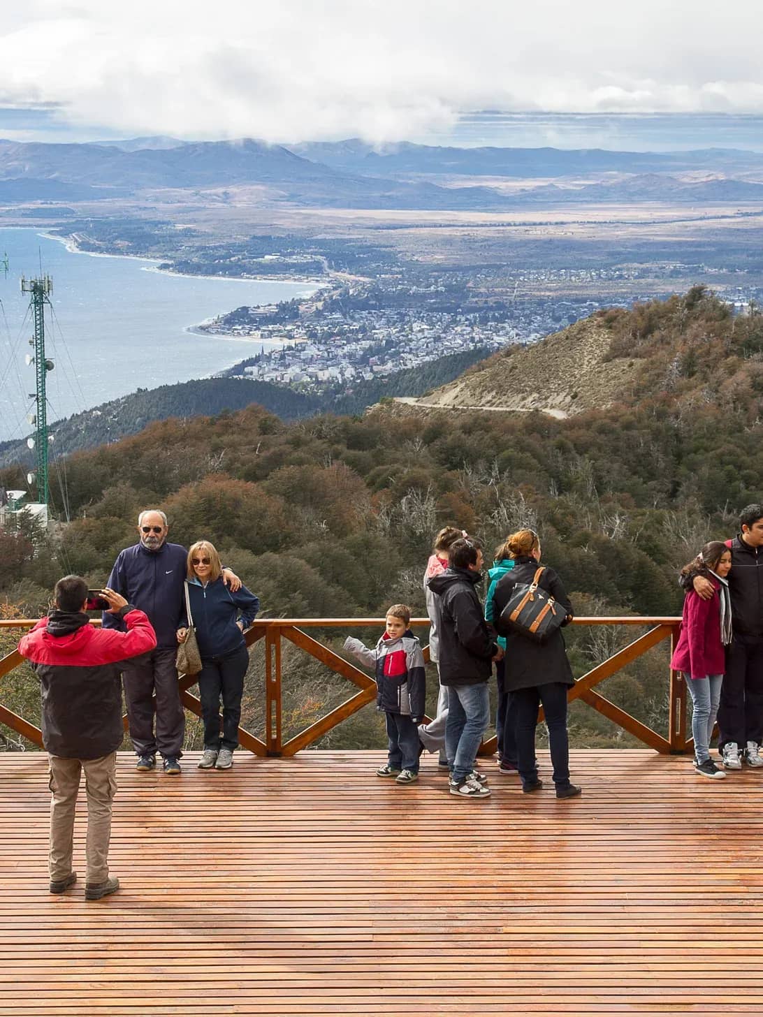 Empleado del Teleférico captura una foto a un grupo de personas en un deck panoramico con el lago nahuel huapi y montañas de fondo